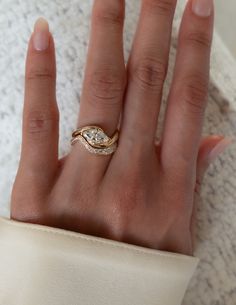 a woman's hand wearing a gold ring with a diamond on the middle finger