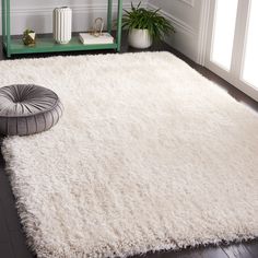 a white rug with a round pillow on the floor