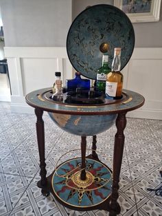 an antique globe with liquor bottles on top sits in the middle of a tiled floor