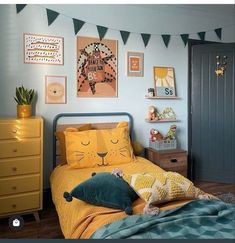 a child's bedroom with blue walls and yellow bedspread, wooden dressers and pictures on the wall