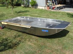 a metal boat sitting on top of a lush green field