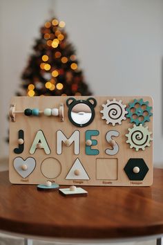 a wooden sign that says james on it with various items around it and a christmas tree in the background