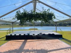 a stage set up under a tent for an outdoor event with water in the background