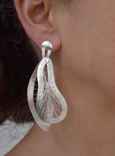 When you’re ready to make a statement, our Sew Weave Earrings are a perfect choice. Every stitch in these two-piece kinetic earrings is carefully placed to create an intricate flow of pattern and movement. The two pieces are joined together with a sterling silver rivet, which allows them to move as you move in the most elegant way. Available in small and large sizes. Details: Your choice of Oxidized Argentium silver or Bright Argentium silver Fine silver stitching Measures: Small size: 2 1/4" x Modern Teardrop Sterling Silver Wrap Earrings, Modern Sterling Silver Teardrop Wrap Earrings, Modern Pierced Wrap Earrings As Gift, Modern Handmade Teardrop Jewelry, Modern Handmade Long Drop Linear Earrings, Unique Teardrop Wrap Earrings, Contemporary Pierced Teardrop Jewelry, Modern Handmade Dangle Wrap Earrings, Contemporary Handmade Teardrop Jewelry