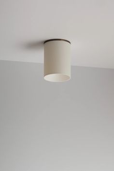 a white lamp hanging from the ceiling in a room with gray walls and flooring