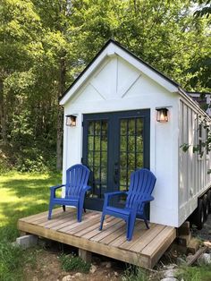 two blue chairs sitting on top of a wooden platform next to a small white building