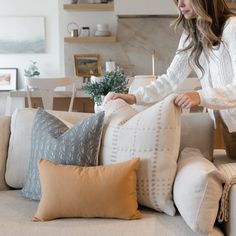 a woman placing pillows on a couch in the living room