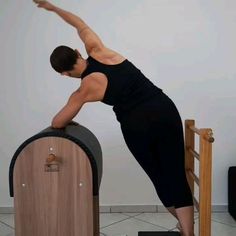 a woman standing on top of a wooden barrel in front of a wall and holding her arm out