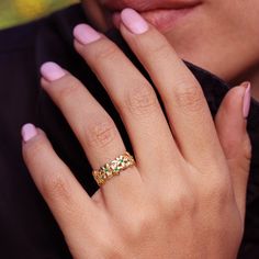 a close up of a person's hand with a ring on their finger and pink nails