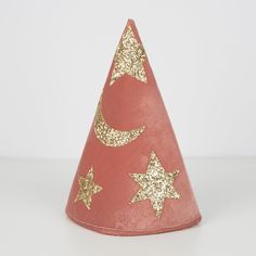 a pink party hat with gold stars and crescents on it, sitting on a white surface