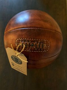 an old leather football is on display with a tag hanging from it's side