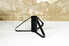 a black metal object sitting on top of a white table next to a stone wall