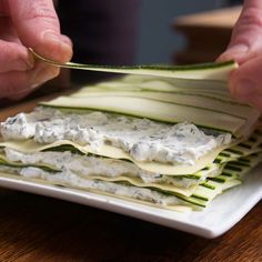 a person cutting up food on top of a white plate with cucumber slices