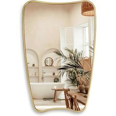 an oval mirror reflecting a bathtub in a room with white walls and flooring