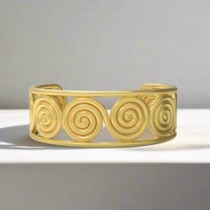 This stunning cuff bracelet is fit for the gods! Here, a timeless "figure-eight" spiral repeats across the wrist, within a strong, clean border. The design is based on a series of gold ornaments found within a 16th century BC burial in Grave Circle A, at Mycenae. The grave, which belonged to a woman, was filled with gold jewelry and accoutrements. In ancient Greek mythology, Eupraxia was the personification of well-being. Her name was derived from the ancient Greek word for "good conduct" (Εὐπρα Ancient Greek Mythology, Ancient Greek Words, Gold Vermeil Jewelry, Jewelry Catalog, Gold Ornaments, Vermeil Jewelry, Samoa, Seychelles, 16th Century