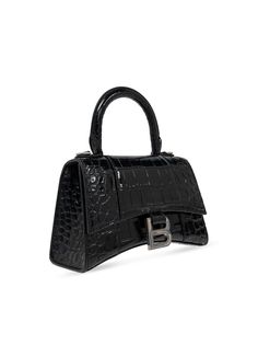 This Balenciaga Hourglass XS Handbag features a glossy black patent finish, crocodile effect embossed leather, silver-tone hardware, and an appliqué logo. The foldover top has a magnetic fastening, and there is a single rolled top handle and an optional adjustable shoulder strap. Inside, the main compartment is roomy and comes with a protective dust bag. The bag measures in at a compact size, with a width of 7.36 inches, a height of 5.08 inches, and a depth of 3.07 inches. Designer Black Bags With Glossy Finish, Black Glossy Business Bag, Designer Business Bags With Glossy Finish, Balenciaga Handbag, Black Balenciaga, Balenciaga Handbags, Balenciaga Women, Messenger Bag Backpack, Small Leather Bag