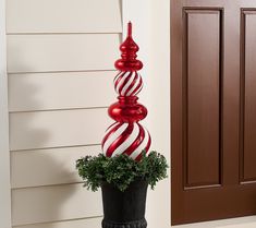 a tall red and white striped glass christmas ornament on top of a potted plant