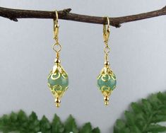 "I created these Wonderful Victorian Style dangle earrings with Green Aventurine Gemstone Beads surrounded by golden beads and beautiful filigree bead caps.   The Genuine Green Aventurine beads are a beautiful true \"jade green\" color and what shows as darker flecks in the pictures are not at all discernible in person - the green is very solid and pure. The bright golden tones of the metal beads create a stunning contrast to the soft green. These are truly beautiful earrings and will work for d Gold Aventurine Beaded Jewelry, Bohemian Gold Jade Earrings, Gold Jade Earrings With Ear Wire, Gold Aventurine Earrings Gift, Victorian Style Earrings, Jade Green Color, Golden Beads, Head Pins, Red Crystals