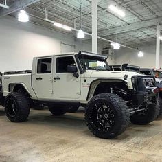 several jeeps are parked in a large warehouse