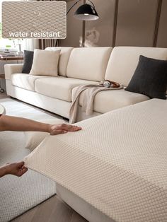 a woman reaching for a mattress on the floor in front of a couch with pillows