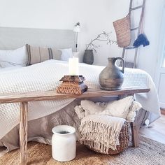 a bedroom with a bed, table and vase on the floor in front of it