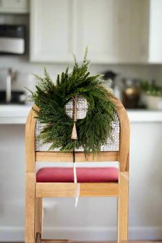 a wooden chair with a wreath on top of it and a red cushion underneath the seat