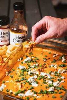 a person cutting up some food on top of a pan with the words spicy bbq chicken dip above it