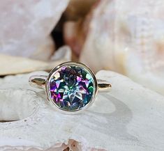 This modern bezel set ring contains a 4.00 ct. natural mystic topaz. The center stone measures 10mm and the band is approximately 2.5mm wide. The ring is available in sterling silver and 14k white, yellow, or rose gold. The mounting is a modern, elegant setting with a high polish finish. Please send me a message if you need a size not listed. This ring can be customized with any color center stone. All items are handmade by me in my shop in Manalapan, NJ. Please message me with any questions. Sh Iridescent Topaz Gemstone Ring, Green Topaz, Mystic Topaz Ring, Solitaire Rings, Bezel Set Ring, Bezel Ring, Morganite Ring, Set Ring, Mystic Topaz