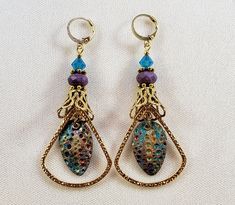 Hand-Painted Earrings. The centerpiece of these earrings are the beautiful hand-painted on copper with resin charms made by Washington State artist Kristi. I accented them with rounded triangle connectors, vintage brass bead caps, purple faceted Czech glass beads and turquoise Swarovski crystal bicone beads. These earrings are 3 inches long including the pure brass round lever back closures. One Of A Kind I can send it gift wrapped (free of charge), if requested. Saturn Earrings, Hand Painted Earrings, Earrings Resin, Painted Earrings, Resin Charms, Bead Caps, Czech Glass Beads, Washington State, Charm Earrings