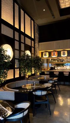 an empty restaurant with tables and chairs next to potted plants on the wall behind them