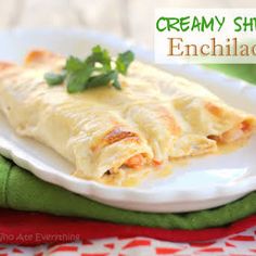 an enchilada on a white plate with green garnish