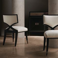 two white chairs sitting next to each other in front of a black and white cabinet