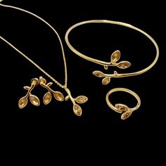 This beautiful collection of nature-inspired jewelry features intricate designs that resemble delicate branches and leaves, with elegant marquise-shaped stones. The collection includes: Gold Plated Set (Yellow Stones): Bracelet: A slender, adjustable bangle with leaf-like yellow marquise stones accenting the branches. The minimalist design gives a chic and timeless appearance. Ring: A matching ring featuring the same leaf motif, with two leaves curving around the finger for a graceful and organic look. Necklace: A fine chain with a pendant shaped like a small branch adorned with two yellow marquise stones. Earrings: Elegant drop earrings that mirror the branch and leaf design, making this set a perfect option for nature lovers seeking a subtle, luxurious touch. Silver Set (Green Stones): B Leaf Necklace With Stone, Luxury Intricate Design Bangle Jewelry, Formal Yellow Gold Leaf Jewelry, Yellow Gold Leaf-shaped Formal Jewelry, Formal Yellow Gold Leaf-shaped Jewelry, Elegant Leaf-shaped Formal Jewelry, Elegant Leaf-shaped Jewelry For Formal Occasions, Elegant Gold Leaf-shaped Jewelry, Elegant Gold Plated Leaf-shaped Jewelry