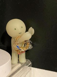 a small figurine holding a ring on top of a counter next to a black wall