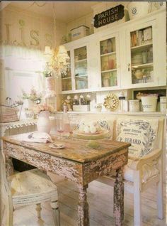 an old fashioned dining room table and chairs in front of a kitchen with white cabinets