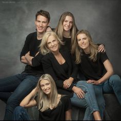 a group of people sitting next to each other posing for a photo on a gray background