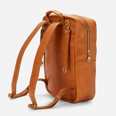 a tan leather backpack with zippers and straps on the front, sitting against a white background