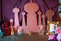 an assortment of decorative items displayed in front of a purple backdrop with a gold frame