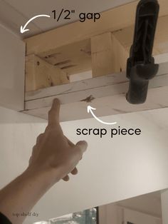 a person pointing to the ceiling in front of a mirror with two screws on it