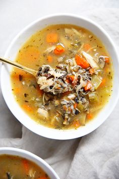 two bowls of chicken and wild rice soup with a spoon in it on a white napkin