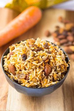 a bowl filled with rice and nuts next to carrots