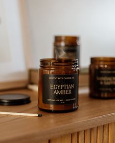 an egyptian amber candle sitting on top of a wooden table next to other jars and candles