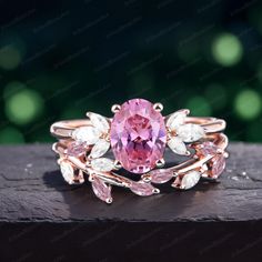 a pink and white ring with leaves around it on top of a piece of wood