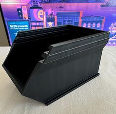 a large black bin sitting on top of a white table next to a tv screen