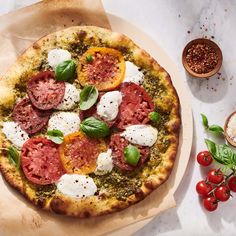 a pizza with tomatoes, mozzarella and basil on it next to other ingredients