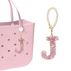 a pink purse with a gold chain hanging from it's side next to an initial charm