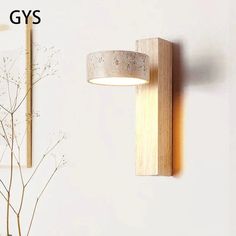 a wall light that is on the side of a wall next to a vase with flowers in it