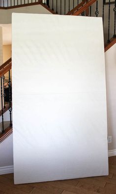 a large white sheet sitting on top of a wooden floor next to a stair case