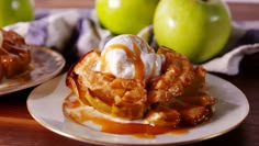 two plates topped with waffles covered in caramel sauce and whipped cream next to green apples