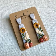 two pairs of knitted pumpkins and sunflowers are hanging from the back of a pair of earrings